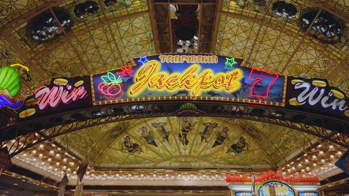 Neon Jackpot sign under a stained-glass ceiling above a casino slot floor in Las Vegas