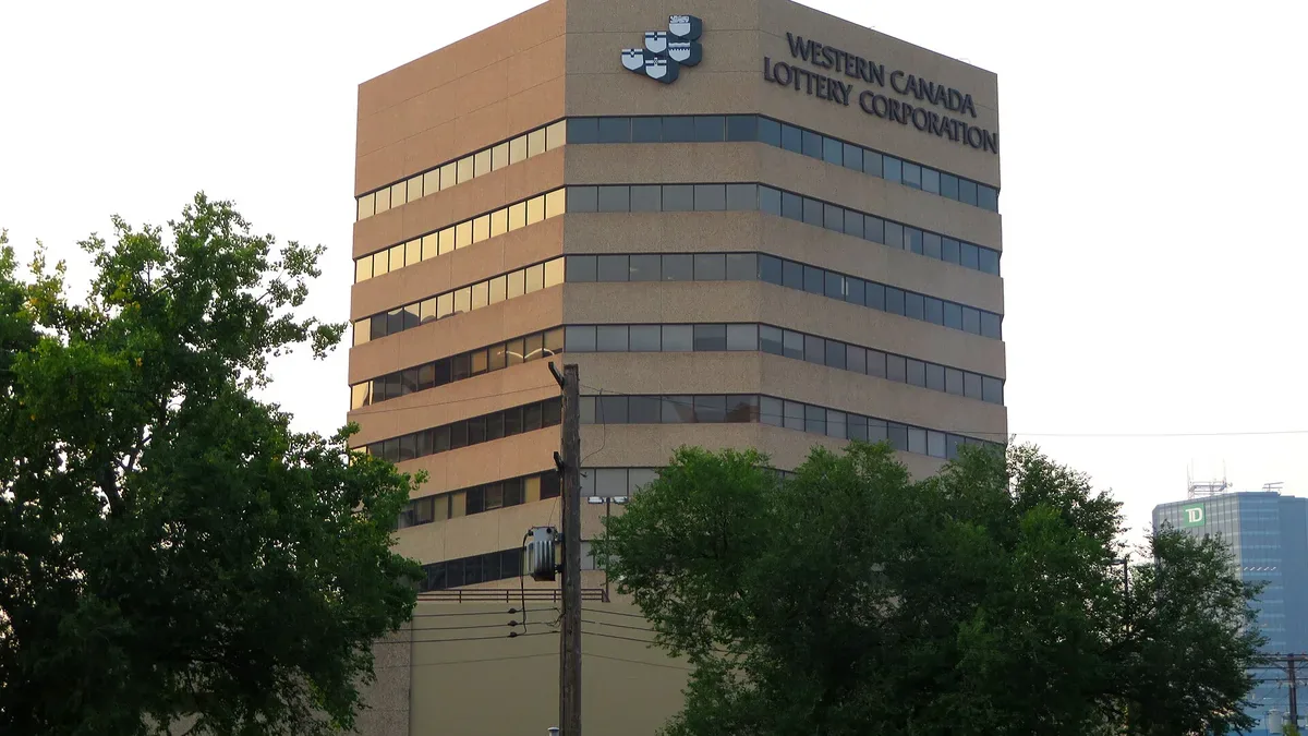 Western Canada Lottery Corporation office tower behind trees in Winnipeg, Manitoba